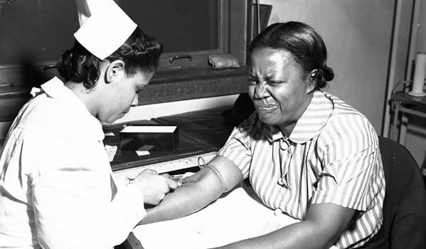 Woman grimacing while having blood drawn.